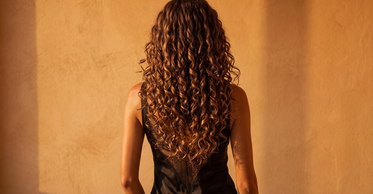 Femme aux longs cheveux bouclés vue de dos
