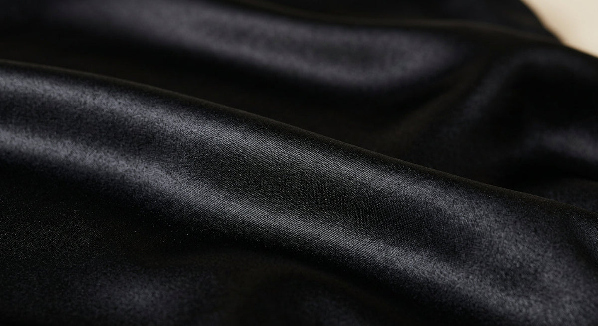 Gros plan sur le satin noir de la taie d'oreiller Paris Curls pour cheveux bouclés